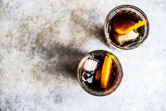 Overhead view of two cola drinks with ice cubes and slices of fresh orange