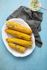 Sweet corn cob with butter on white plate summer food