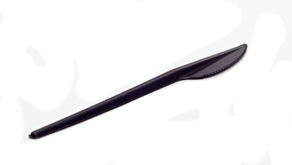 black plastic table knife on white background isolated closeup, disposable plastic tableware.