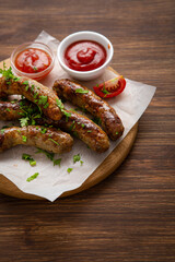 Close up of grilled pork lamb sausage and tomato on wooden surface