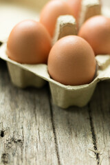 Close-up view of raw chicken eggs in egg box on wooden background