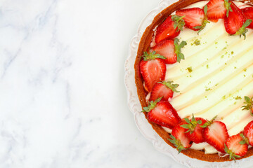 Delicious homemade tart with strawberries, cream cheese or whipped cream, jelly and pistachios. Berry cheesecake. Dessert. Pie. Cake.  Marble background. Top view, copy space