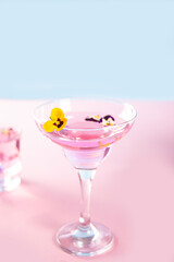 Glass of pink violet purple cocktail decorated flowers viola pancies