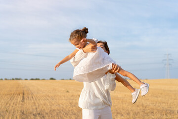 Mother throws up little daughter in air standing wheat field summer day blue sky background