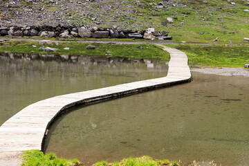 Small floating walkway made of wood planks over the mountain lake