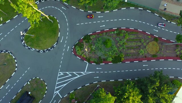 Karting Motion on asphalt road with white markings. Karting Attraction Track: People ride small cars on an asphalt race track: aerial top down drone shot.