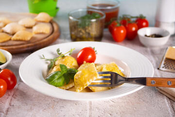 Homemade traditional italian ravioli pasta with basil and tomato cherry vegetables on the table