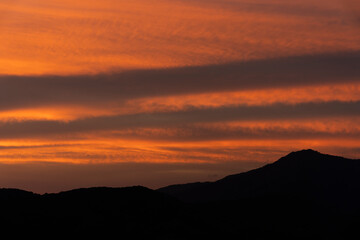 The sky is beautiful in the evening with orange clouds on the shadow of the mountains.