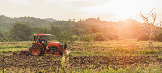 farm tractor with driver plowing to fill the soil for cultivation © PIPAT