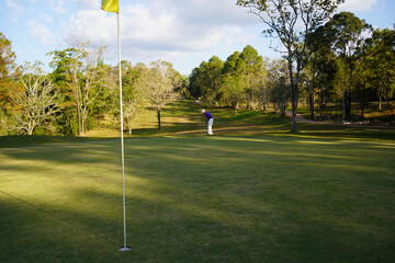 Obraz premium Golfer putting ball on the green golf, lens flare on sun set evening time.