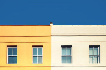 Yellow house, white house and blue sky. Minimalism style with space for text.