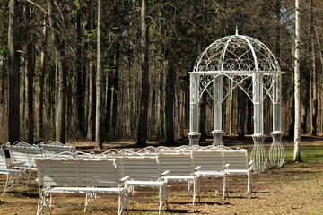 Openwork white gazebo and benches for ceremonial ceremonies in the park