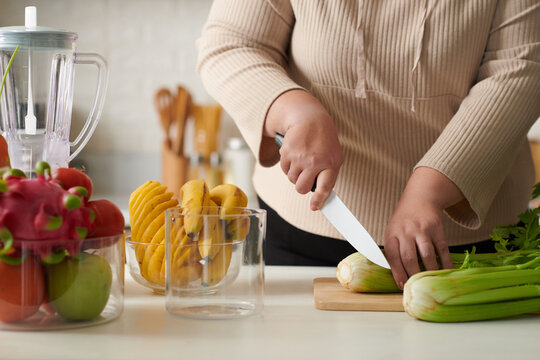 Cropped Image Of Plus Size Woman Cutting Celery For Breakfast Smothie