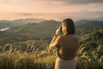 solo woman travel take photo and sightseeing sunrise on mountain at thailand