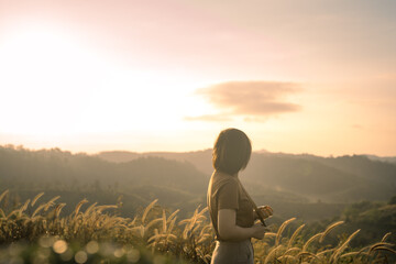 solo woman travel take photo and sightseeing sunrise on mountain at thailand
