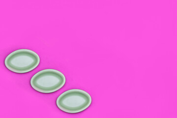 Obraz na płótnie Canvas Pattern of 3 green oval dishes placed in the corner of a vivid pink background with copy space. Flat lay