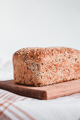 Bread with sesame seeds on a wooden board. Healthy baked bread on a white background. Copy space.