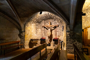 The interior of the Sant Pere church in the medieval village of Pals on the Costa Brava coast showing Jesus Christ crucified in a small stone altar area.