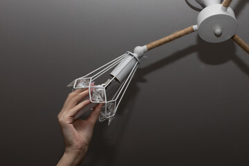 Fototapeta premium woman screwing a lamp into a lamp holder in the dark