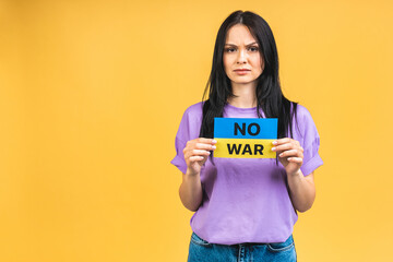 Stop war in Ukraine! Portrait of sad agressive angry woman holding in hands Ukrainian flag isolated over yellow pastel color background.