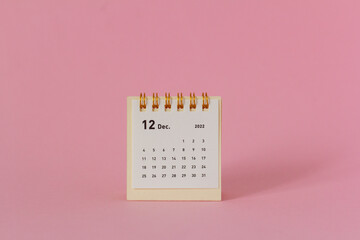 Desktop calendar for December 2022 on a pink background.