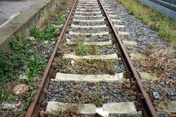 Alte verwitterte Bahnschienen auf Bahnhofgeländen in Stadt im Frühling 