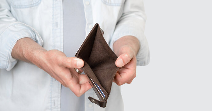 A man holds an empty brown purse with no money. Male hands. Bankruptcy, poverty. Isolated gray background