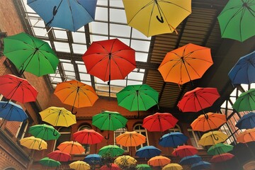 Bunte Regenschirme unter Glasdach von Bahnhofsgebäude 
