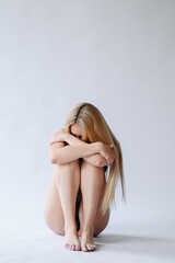Fototapeta premium The body of a slender tanned woman on a white background. Closed Pose Girl