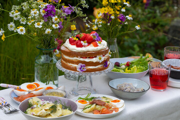 Obraz na płótnie Canvas Scandinavian midsummer meal with strawberry and cream cake, potato salad, salmon and eggs