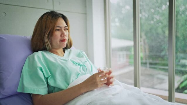 Female lying in bed is taking vitamins or medicine in the hospital, people healthcare concept