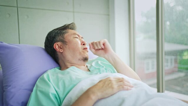 Portrait of sick man coughing lying in hospital, male patient infected with covid-19 virus suffering from severe cough in hospital ward