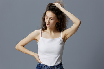 Irritated angry curly beautiful woman in basic white t-shirt trying to calm down holding her hair posing isolated on over gray blue background. People Lifestyle Emotions concept. Copy space