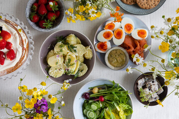 Scandinavian midsummer meal with strawberry and cream cake, potato salad, salmon and eggs