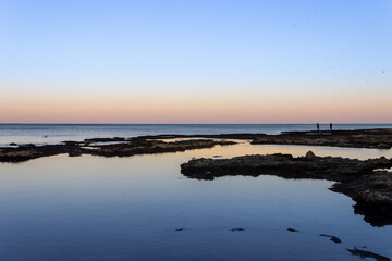 Fototapeta premium Sunrise reefs at the beach in Acre, birds and fishermen