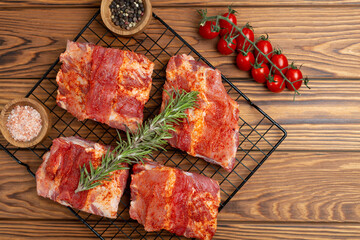 Portioned pieces of pork ribs in spices and marinade on a grill for cooking in BBQ sauce on a wooden background, flat lay, open space