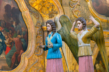 Obraz premium Perm wooden sculpture. Angels in the temple. Wooden carved wooden angels. Ancient sculptures in the church. Angels in yellow and blue robes. Ancient masterpieces of wooden architecture.