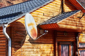 satellite dish on the wall of a wooden house