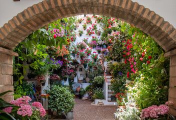 Entrance through an arch to a patio full of flowers in spring , Córdoba, Spain.