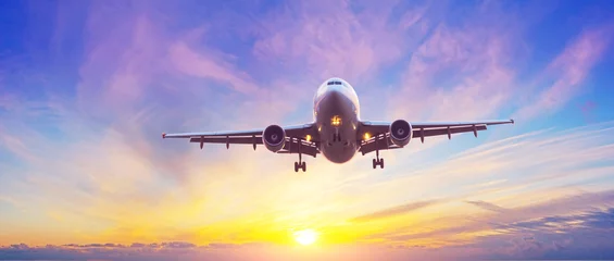 Poster Panoramisch zicht op het silhouet van een vliegtuig dat landt met verlengd landingsgestel, lucht met verschillende soorten wolkengradiënt verlicht door de avondzon die de horizon verlaat. © aapsky