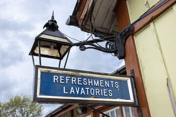 Obraz premium Old weathered blue wooden sign saying Refreshments lavatories sign at Bolton Abbey railway station, Yorkshire, UK