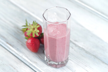 Traditional ayurvedic healthy drink with strawberries of yogurt and ice cube with drinking