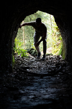 Silhouette of a person entering a small cave. Man exploring the interior of a mysterious cave.