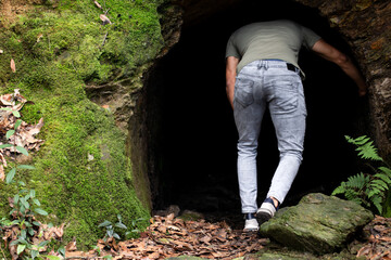 Man entering a strange cave. Curious man entering a cave exploration adventure.