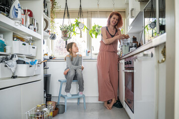 Family of cheerful mother and her little daughter preparing dinner together