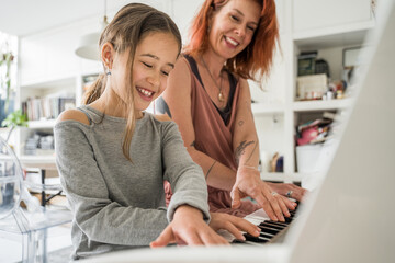 Mom teaches her little daughter to play the piano