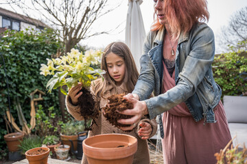 Mother and her child working at the garden while replacing plants