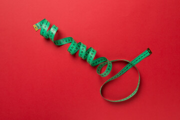 Green measuring tape on color background, top view