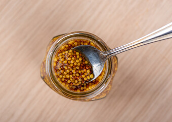 A metal spoon in a jar of Dijon or French mustard.