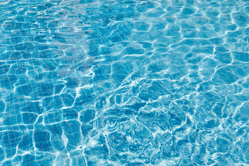 Fototapeta na wymiar Clear water surface with ripple wave splashes and drops in swimming pool. Abstract turquoise or blue texture water wave and sunlight shadow reflections for background.